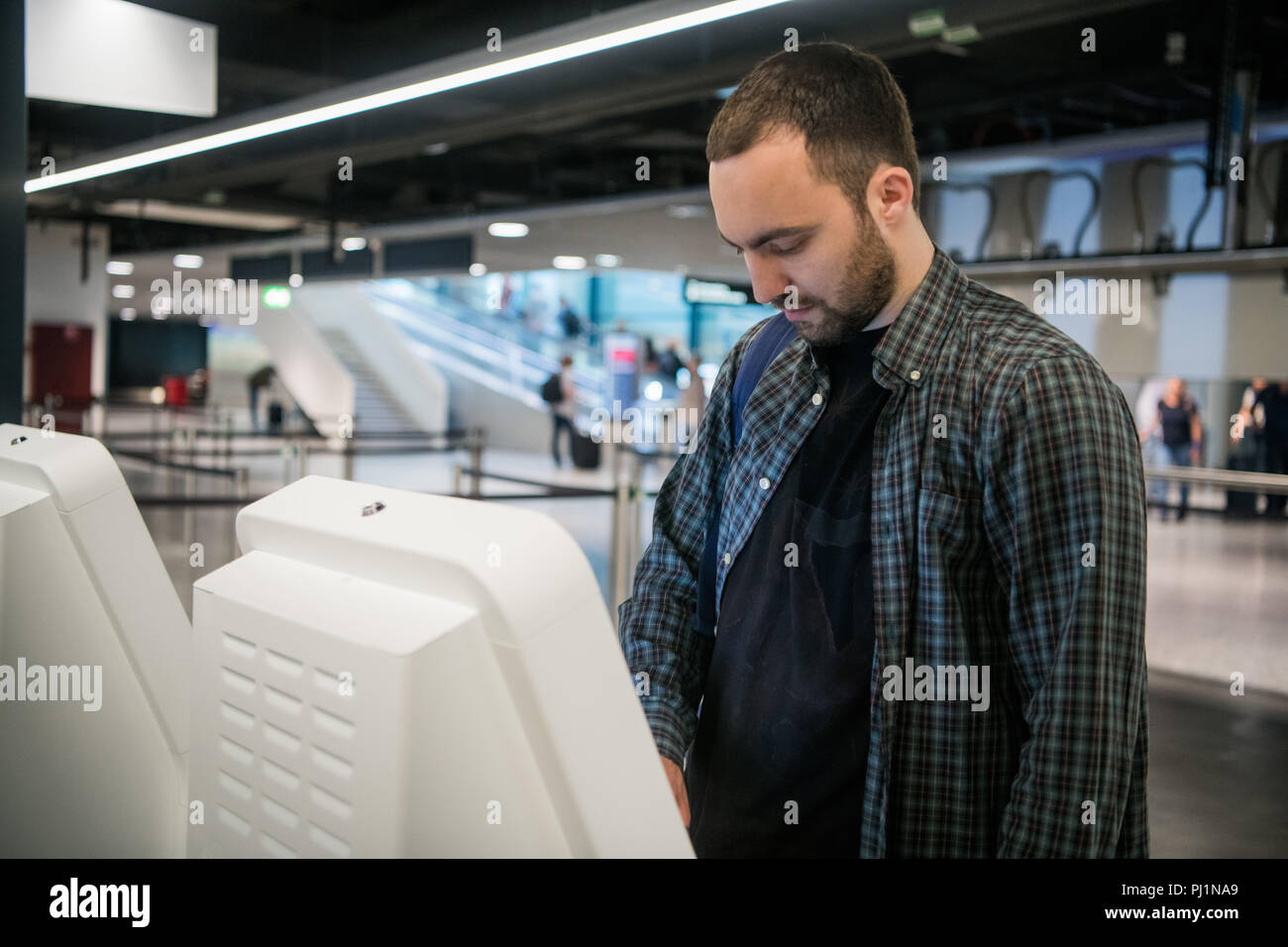 Young man with backpack touching interactive display using self service ...
