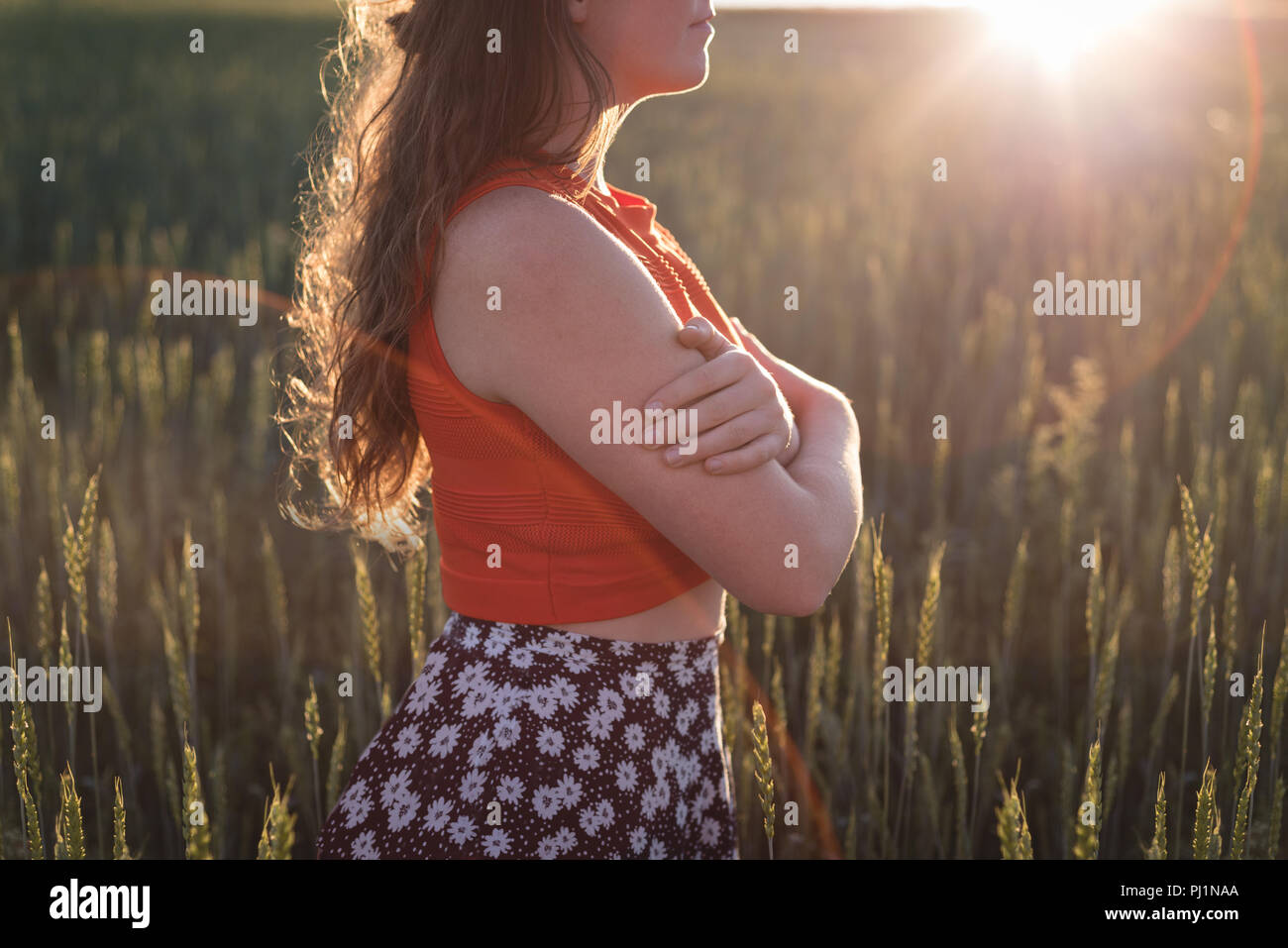 Woman standing with arms crossed in the field Stock Photo