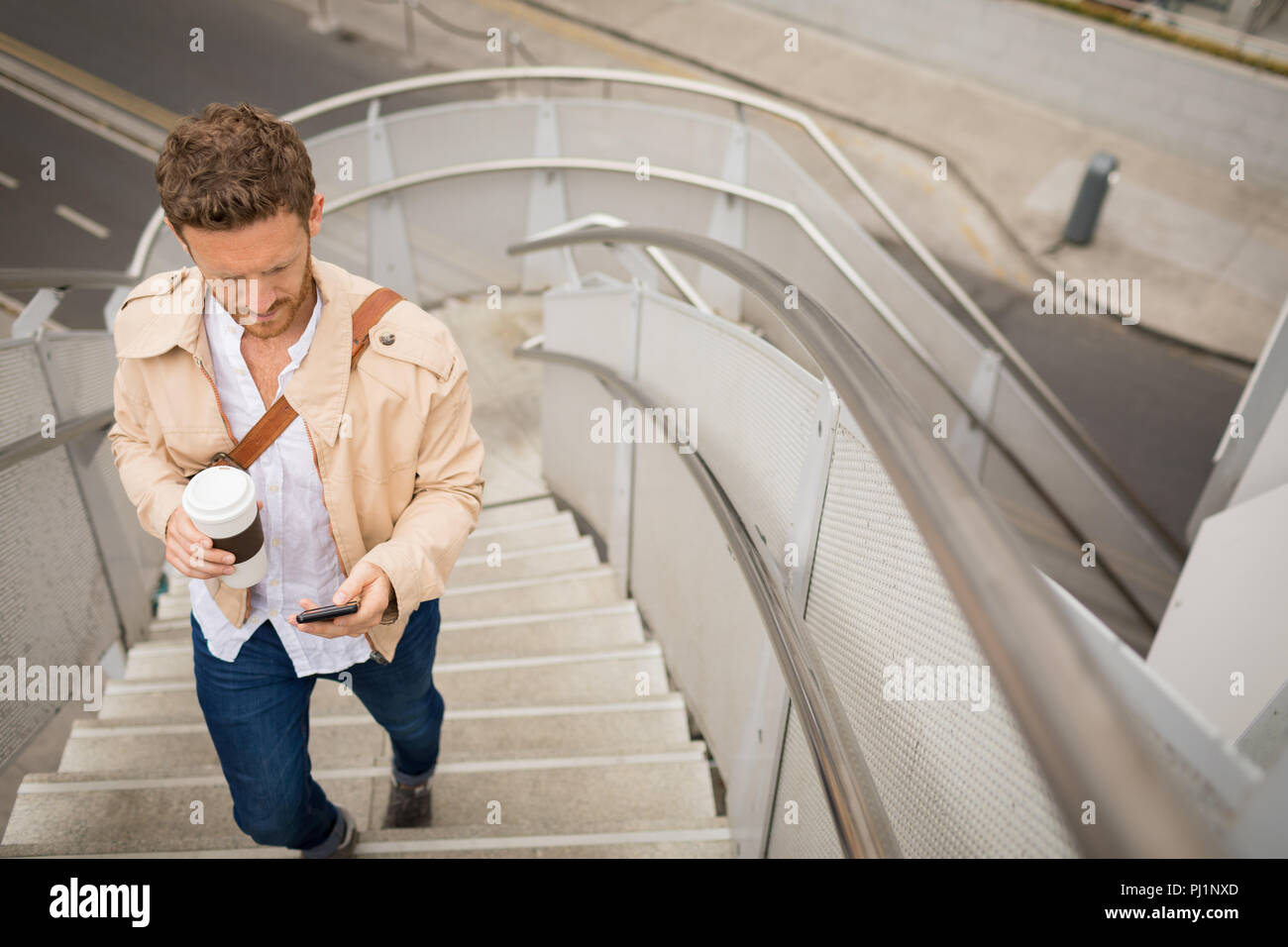 Man walking up stairs while using mobile phone Stock Photo Alamy