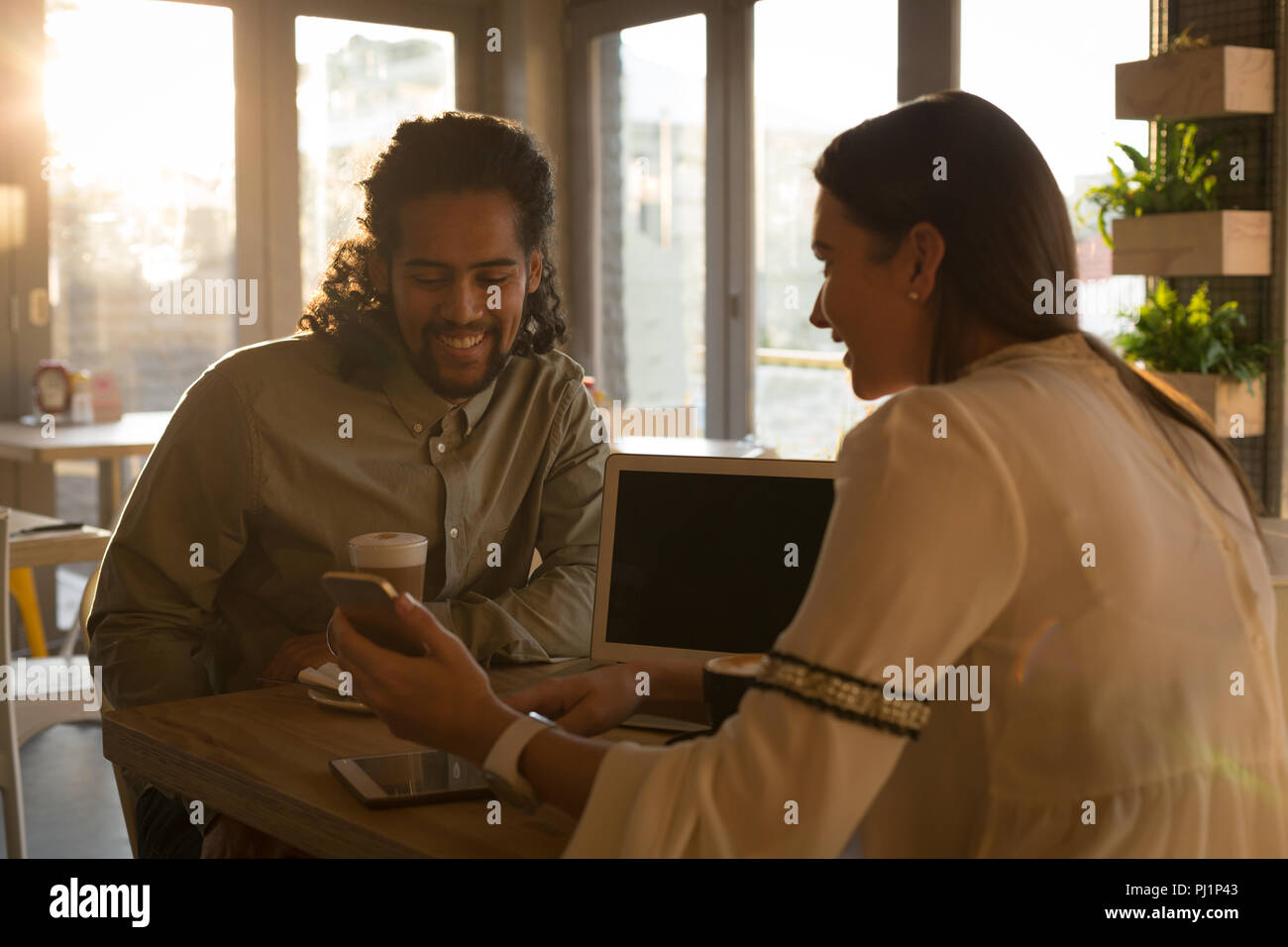 Couple discussing on mobile phone in cafe Stock Photo