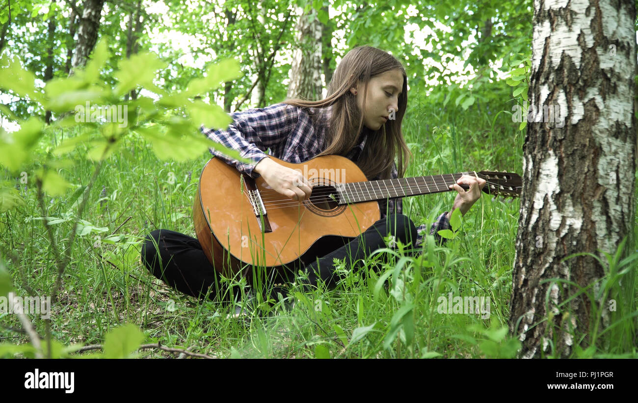 Young girl in forest with guitar in the garden. Teenage girl playing the  guitar in nature. Girl play solo guitar in green nature park Stock Photo -  Alamy