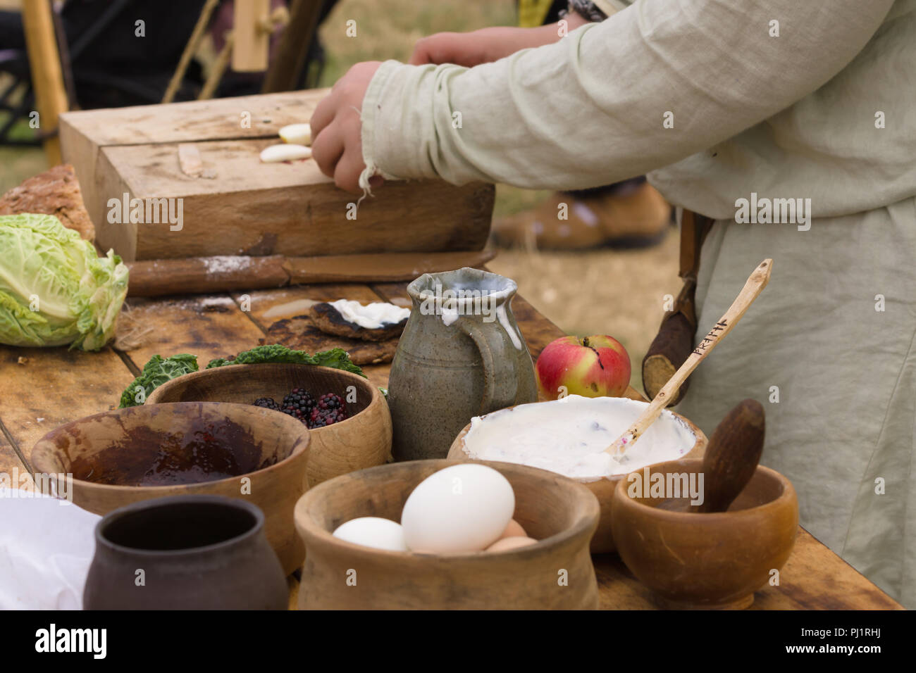 Medieval food preparation including bread, butter, cheese, fruit in wooden bowls or trenchers Stock Photo