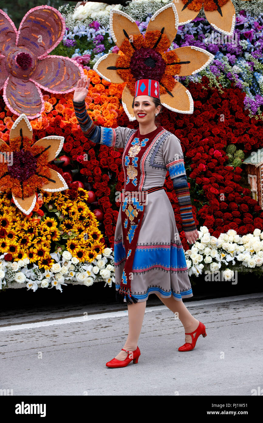 A woman waves next to a float on the route of the 2017 Tournament of Roses Parade, Rose Parade, Pasadena, California, United States of America Stock Photo