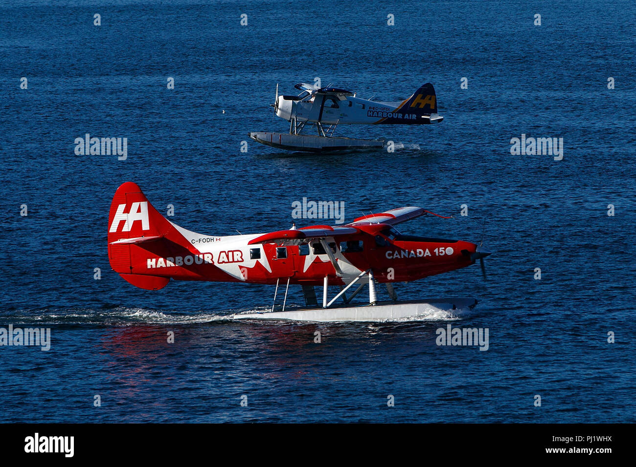De Havilland Canada DHC-3T Vazar Turbine Otter (C-FODH) operated by Harbour Air with the Canada 150 Livery taxies past De Havilland Canada DHC-2 Mk.1 Beaver (C-GFDI) operated by West Coast Air, Vancouver Harbor, Vancouver, British Columbia, Canada Stock Photo