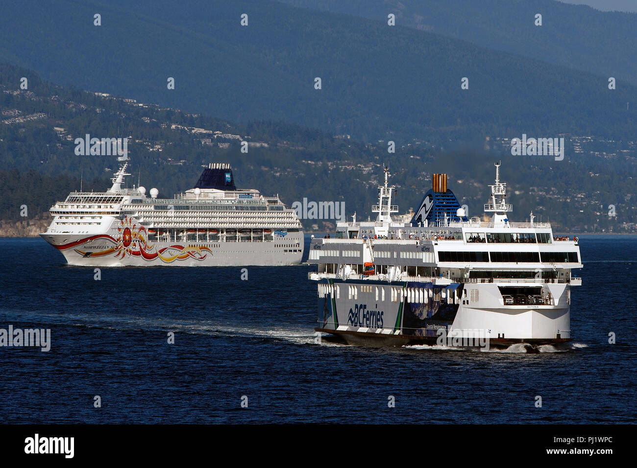 MV Coastal Renaissance, coastal class ferry, operated by BC Ferries passes the Norwegian Sun cruise ship operated by Norwegian Cruise Lines, Vancouver Harbor, Vancouver, British Columbia, Canada Stock Photo