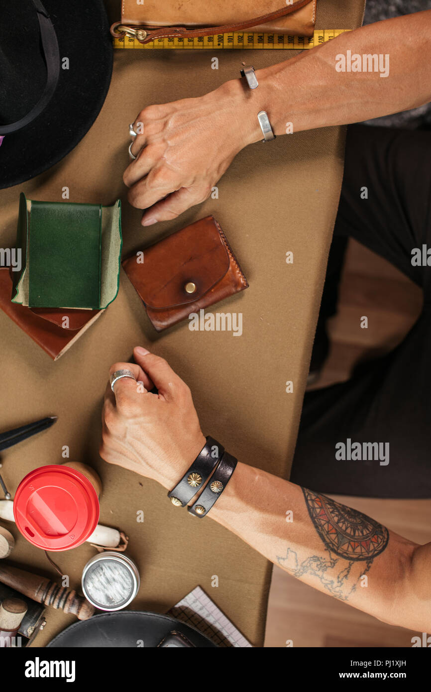 Leather goods master and handmade leather wallets. Workflow in the workshop. Stock Photo