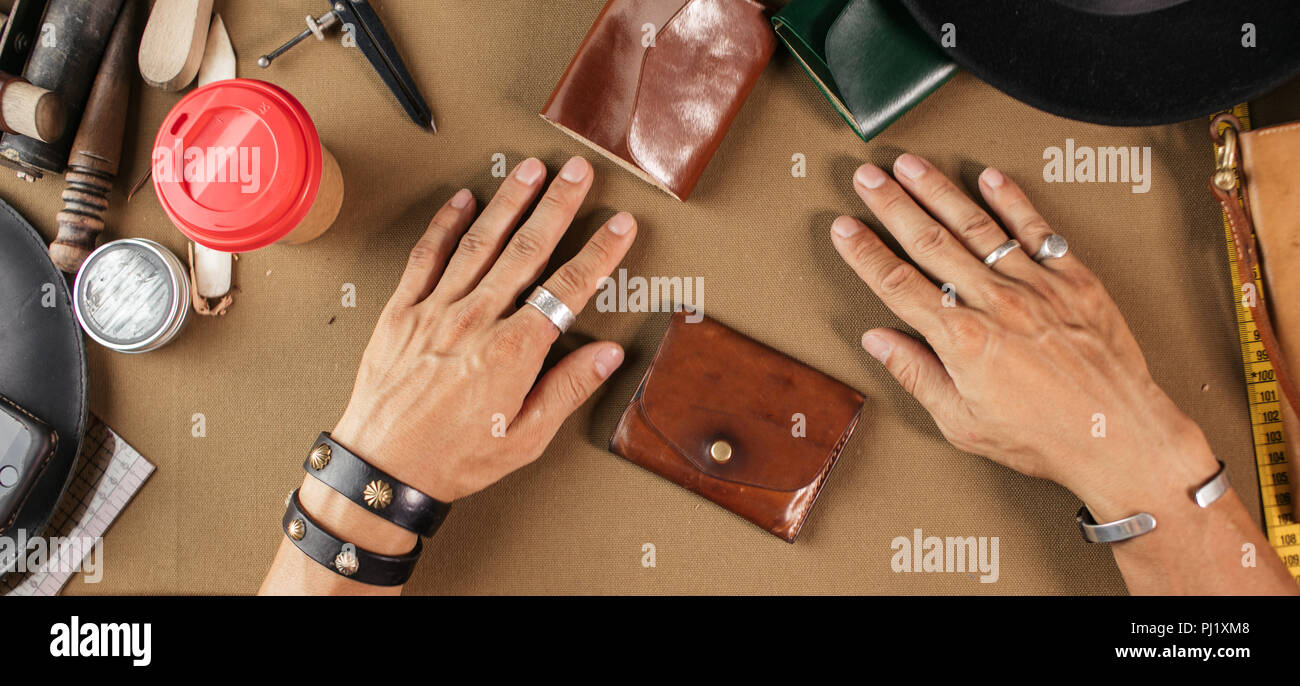 Leather goods master and handmade leather wallets. Workflow in the workshop. Stock Photo