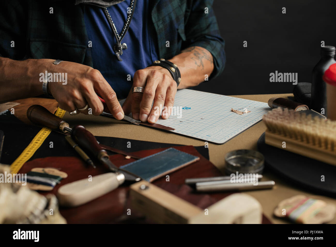 Leather goods master and handmade leather wallets. Workflow in the workshop. Stock Photo