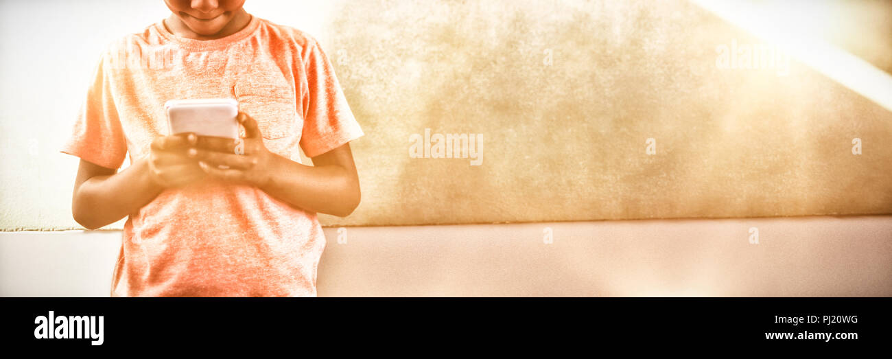 Boy using cellphone against greenboard in school Stock Photo