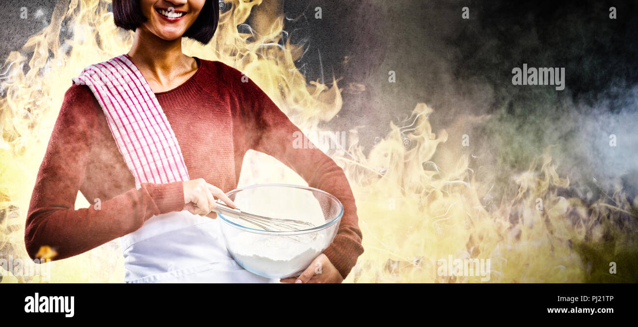 Composite image of smiling female chef mixing flour in bowl with whisk Stock Photo