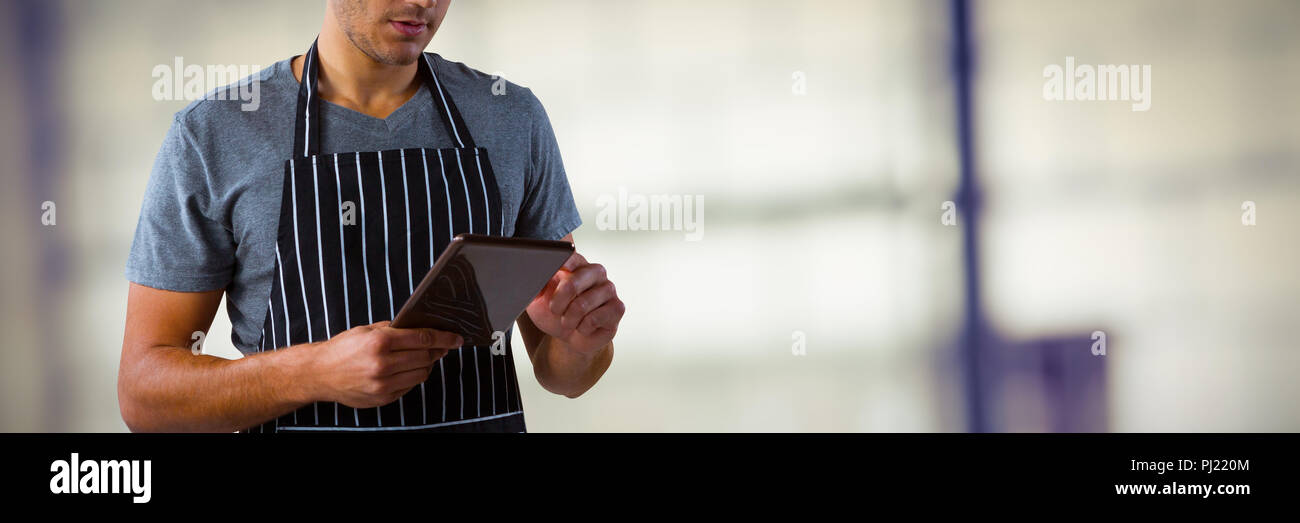 Composite image of male waiter using digital tablet Stock Photo