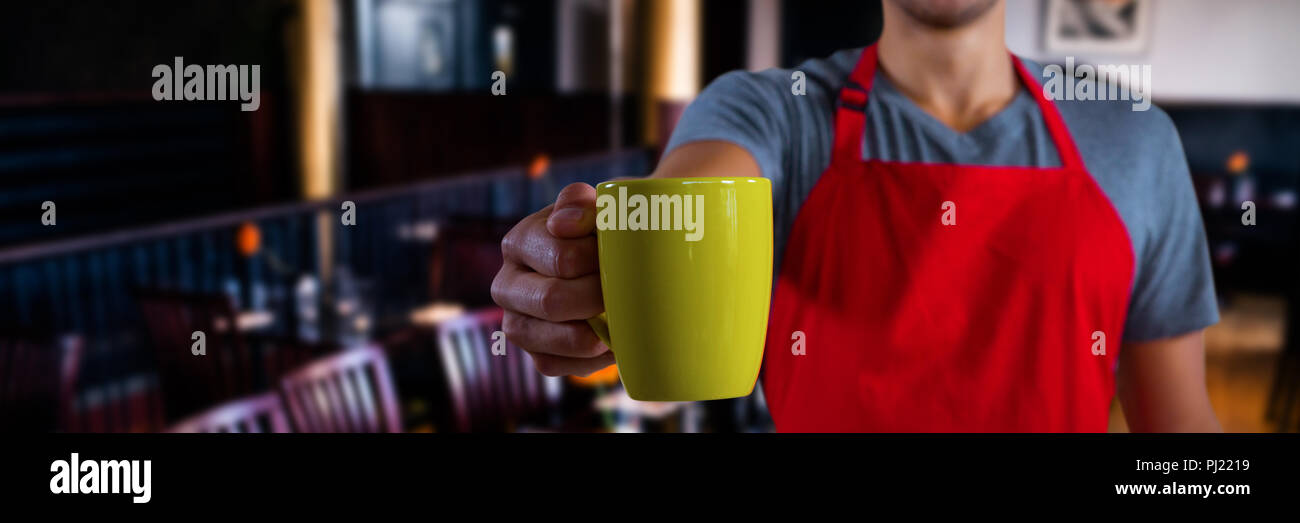 Composite image of male waiter holding coffee mug Stock Photo