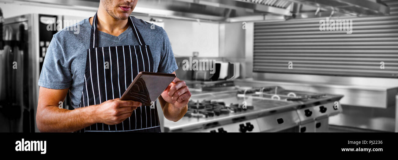 Composite image of male waiter using digital tablet Stock Photo