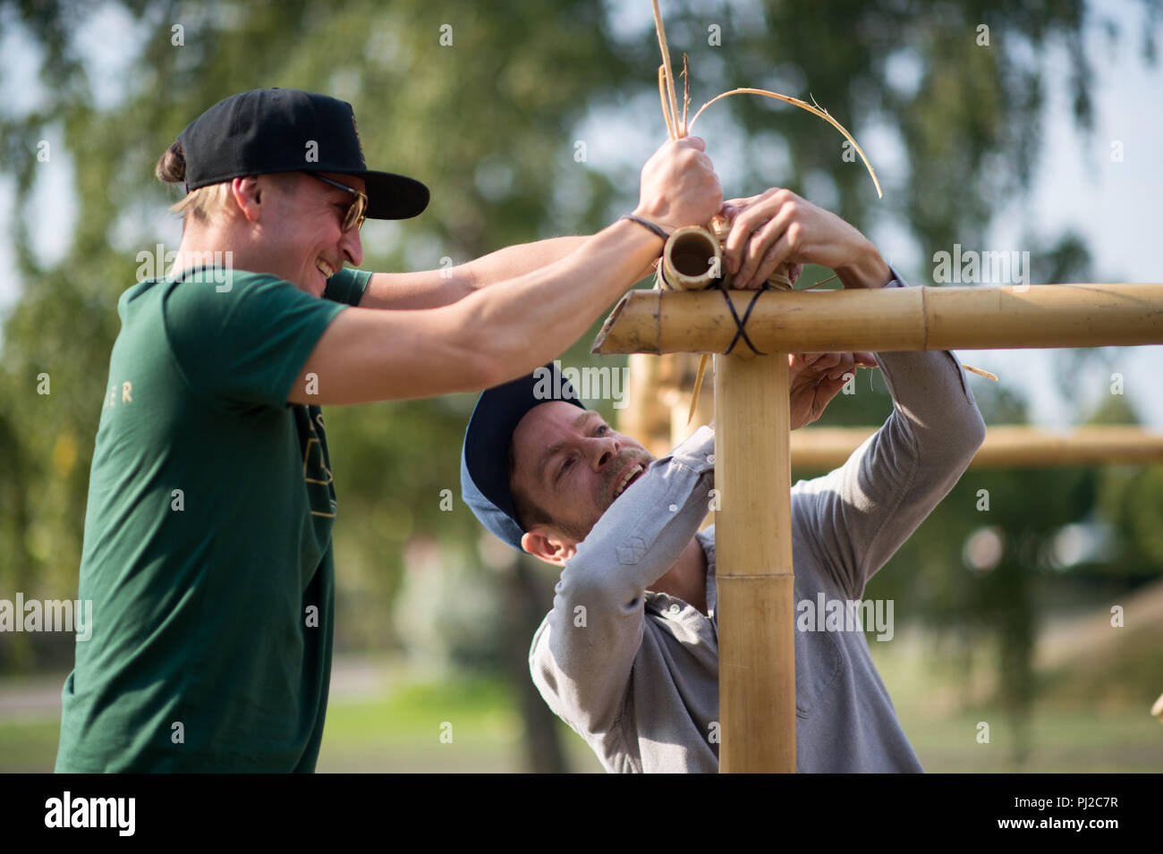 04.09.2018, Saxony-Anhalt, Magdeburg: Manfred Gramer (l) and Stepahn Murer  of the "Kulturanker" association fix the bamboo poles on a pavilion under  construction in the Elbauenpark. A larger edition of the bamboo building,