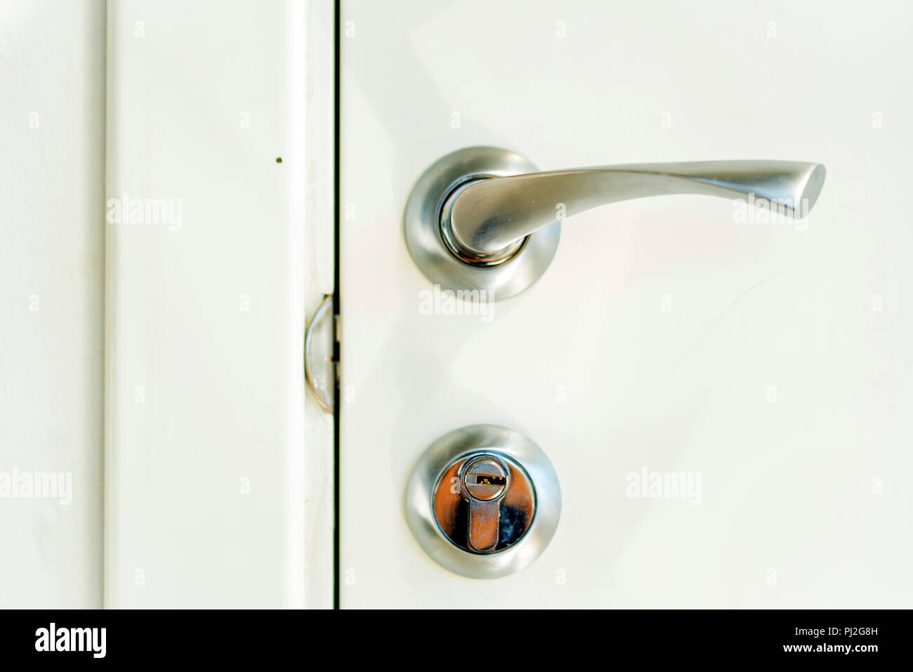 Metal door handle and lock on white door Stock Photo - Alamy