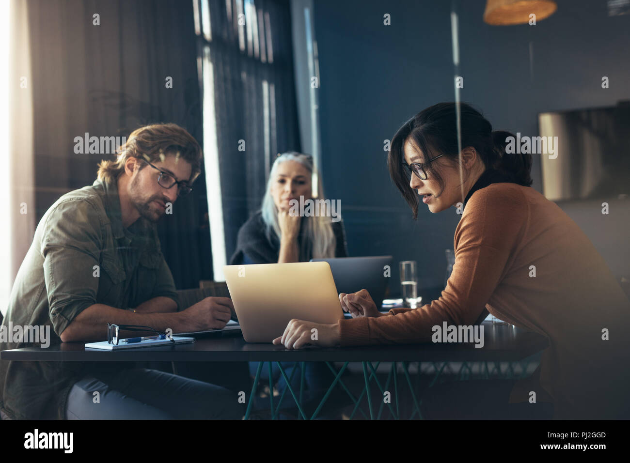 Business woman sharing her ideas with laptop to colleagues. Business people meeting in office and discussing over new project. Stock Photo