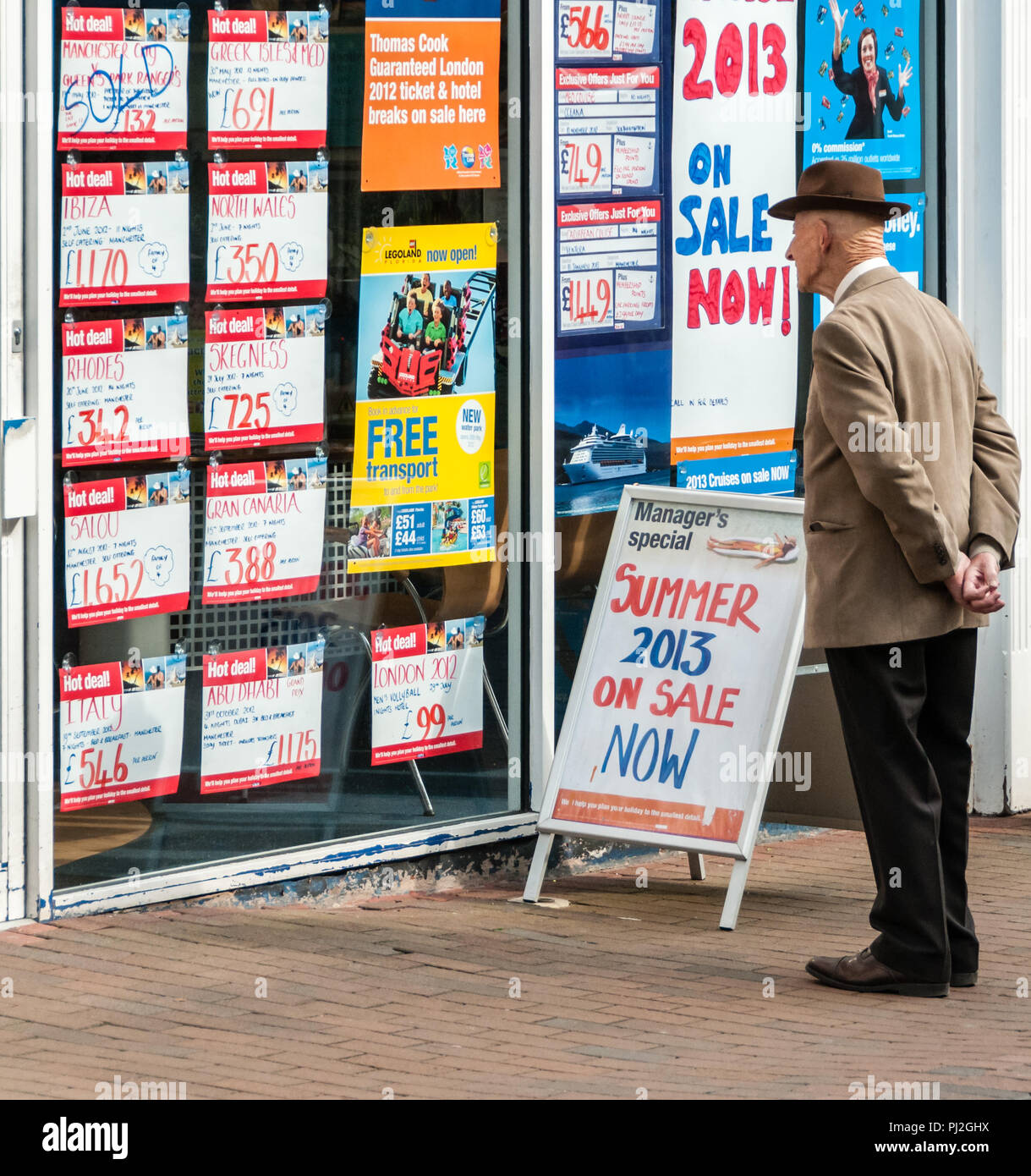 Elderly man looking at holiday offers in a travel agent's shop window in Macclesfield Stock Photo