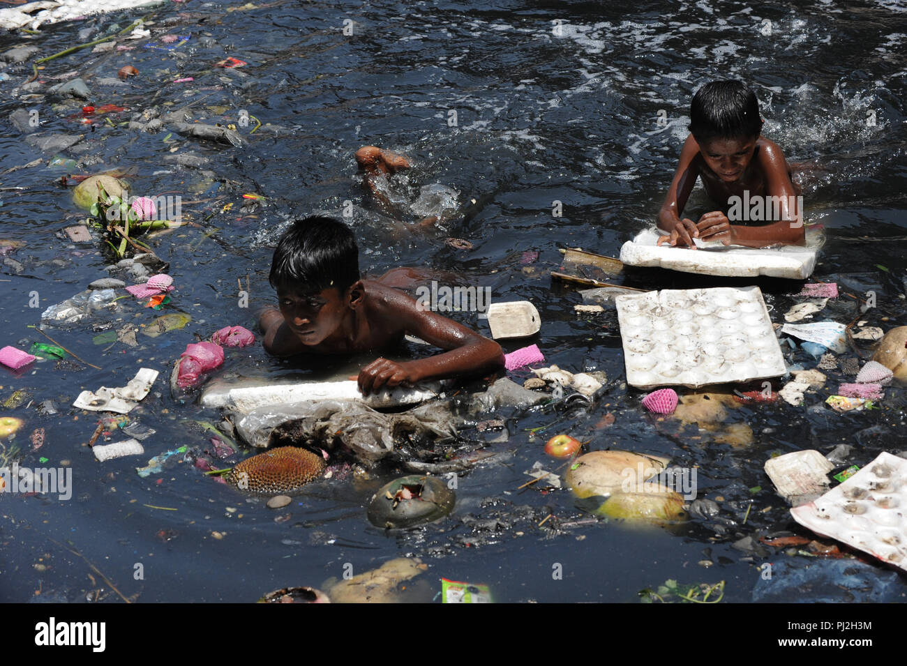 Dhaka, Bangladesh - April 22, 2012: Children Swim in Polluted Buriganga River in Dhaka, Bangladesh. The water of river Buriganga became black because  Stock Photo