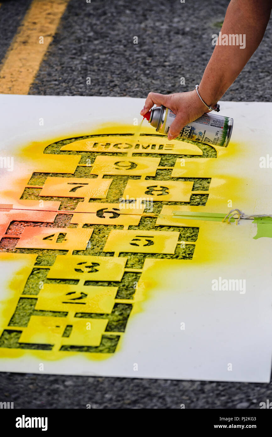 Spray painting a city street using a stencil and spray can Stock Photo