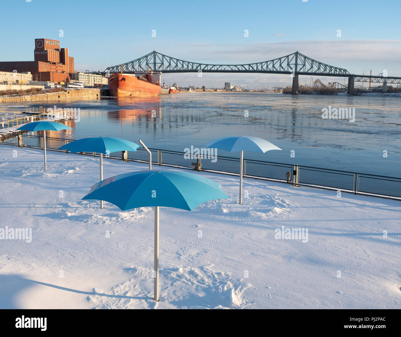 The Clock Tower Beach in Montreal under snow with the St. Lawrence River with the Molson brewery and a large ship in the background. The Jacques Carti Stock Photo