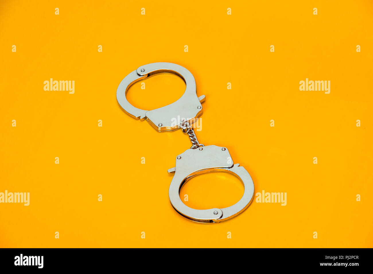 Metal handcuffs isolated on yellow background Stock Photo - Alamy
