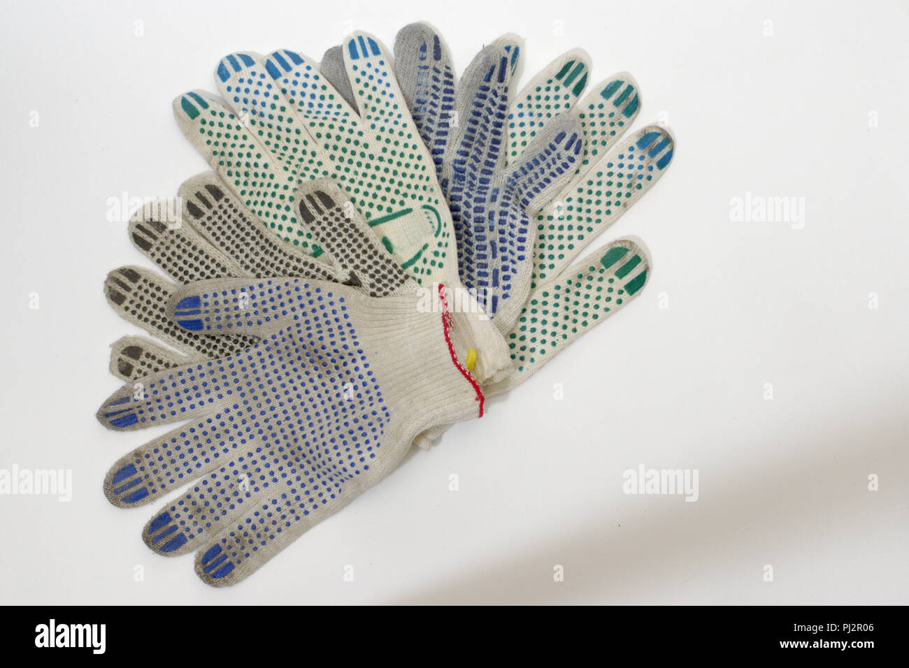 cotton multicolored gardening gloves of white woven textile, with rubber  dots, beautifully arranged in fan shape by palms up Stock Photo - Alamy