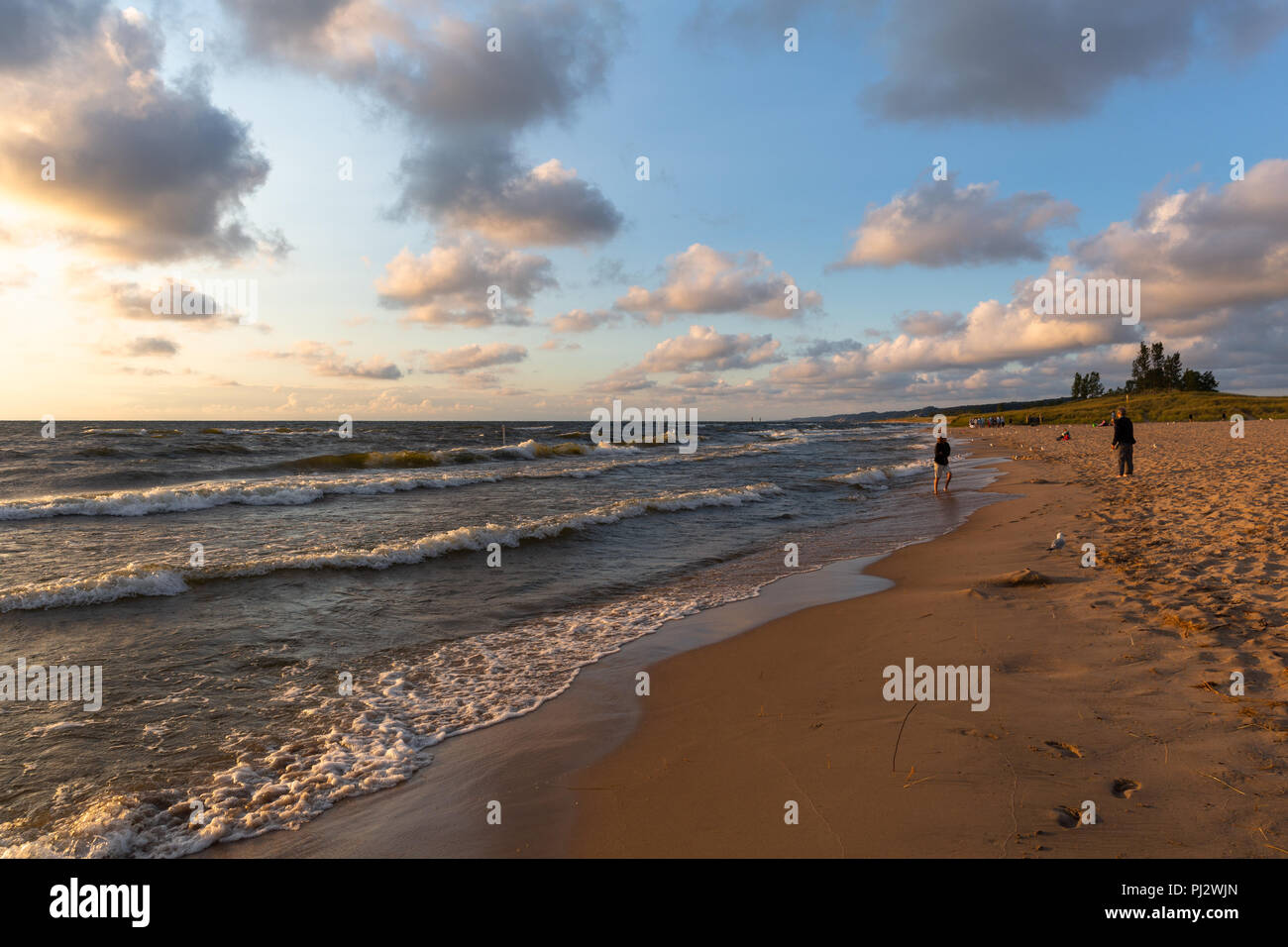 Oval Beach at Sunset with light waves and clouds in a blue sky ...