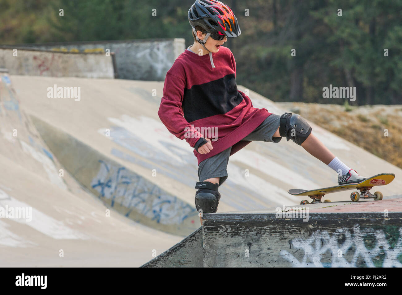 Young, 12 year old, handsome boy, wearing skateboard equipment and  skateboarding. Colorful helmet, knee pads, elbow pads, shorts, Model  Released Stock Photo - Alamy