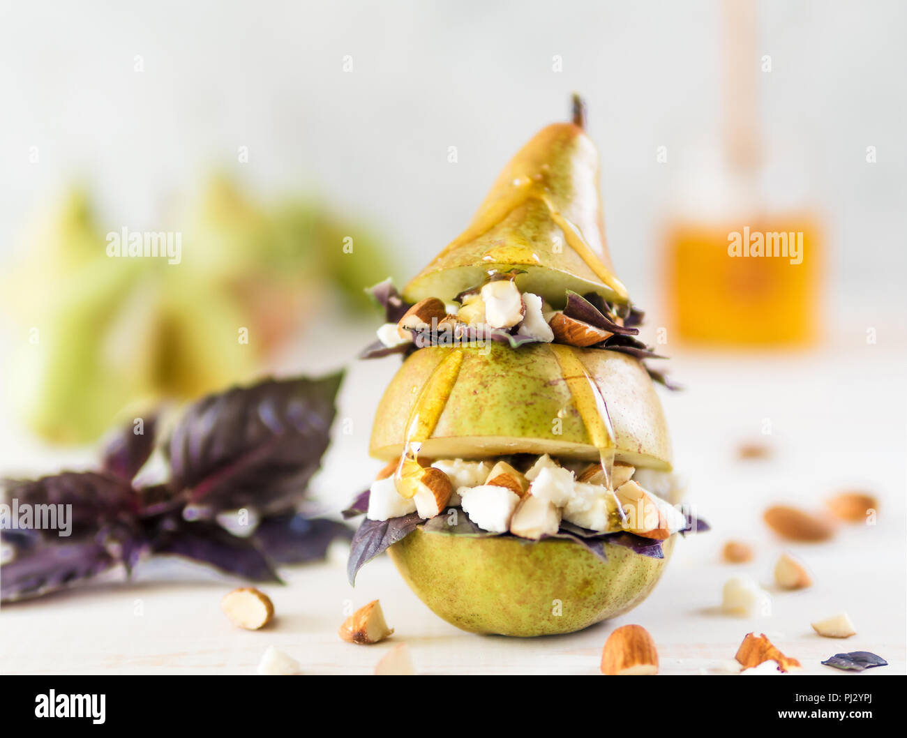 Ready-to-eat fun salad with pear, cheese, nuts, purple basil leaves, honey. Ideas and recipes for healthy breakfast, dinner, appetiezer, salad. Can use for design cheese dairy. Copy space for text Stock Photo