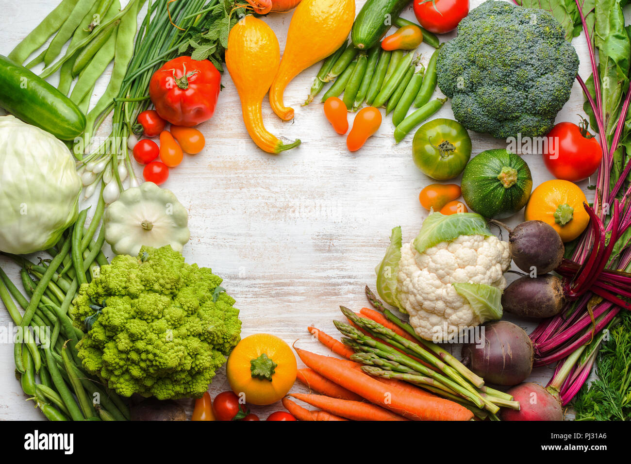 Fresh farm produce, colorful frame made of organic vegetables and herbs on white wooden background, healthy background, copy space for text, top view, selective focus Stock Photo