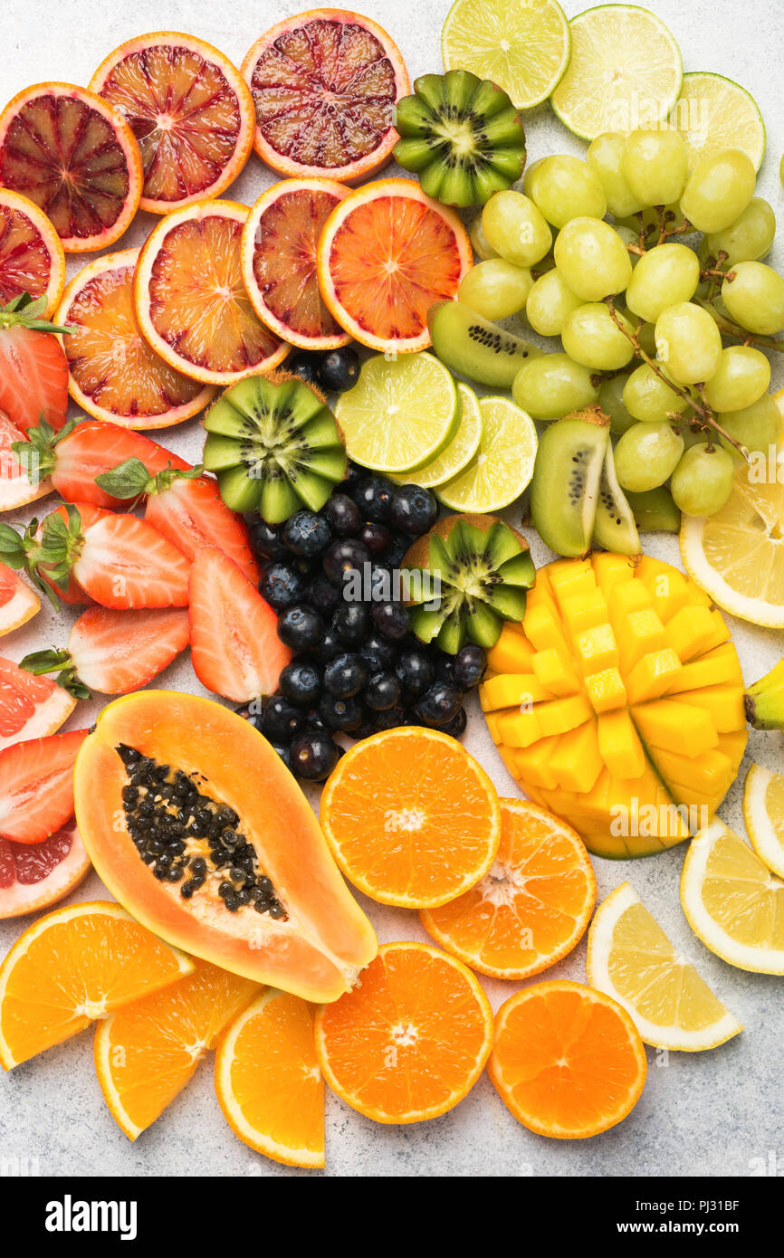 Healthy colourful fruits in rainbow colours background, strawberries, mango, grapes, bananas, grapefruit on the off white table, top view, selective focus Stock Photo