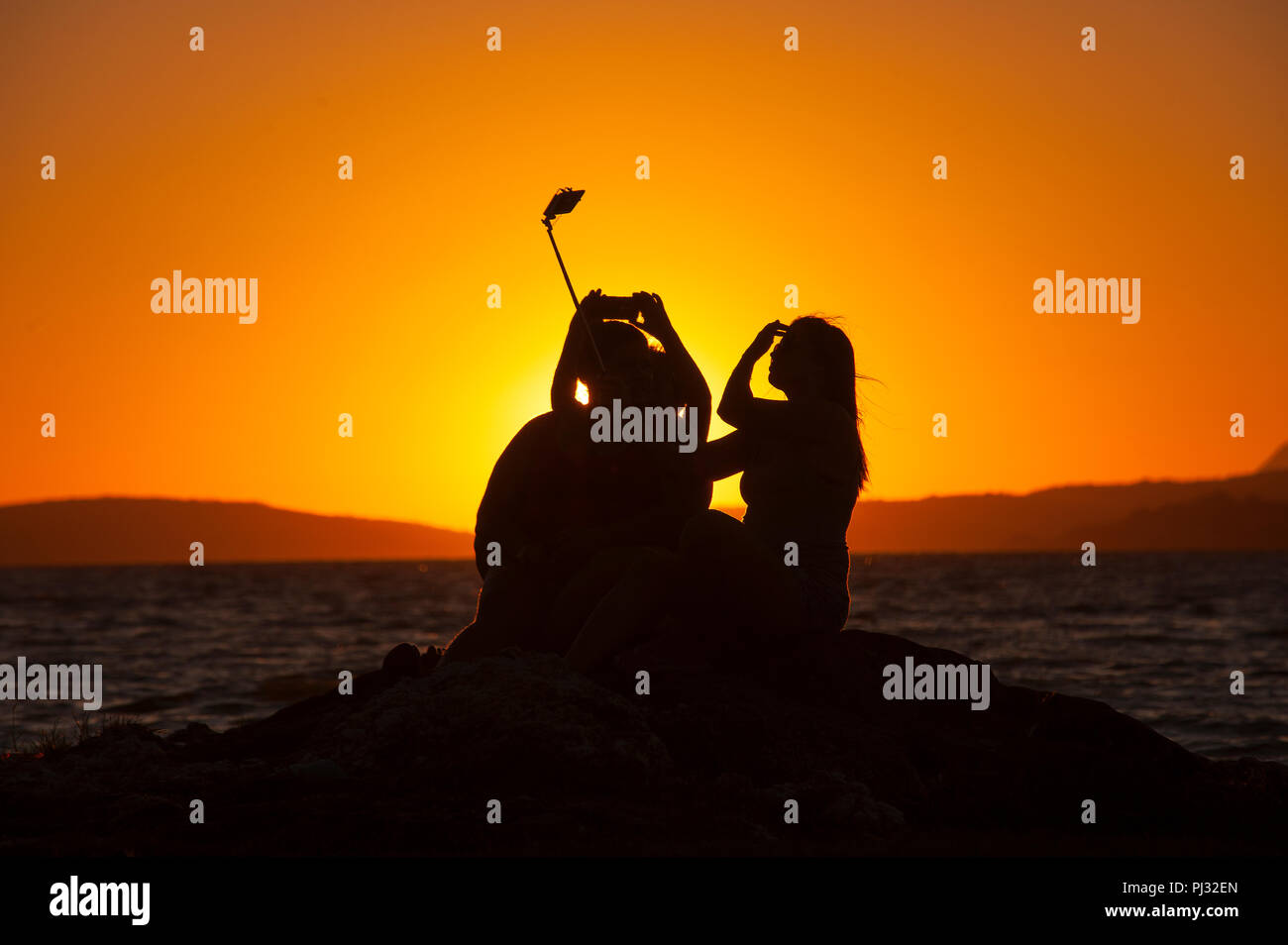 Girls taking selfies at sunset, Lagoon of Maricá, Maricá, Rio de Janeiro, Brazil Stock Photo