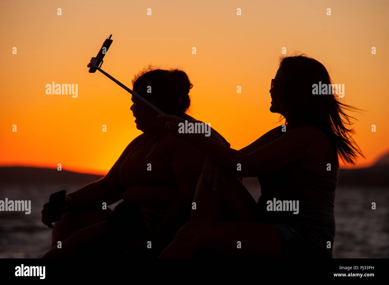Girls taking selfies at sunset, Lagoon of Maricá, Maricá, Rio de Janeiro, Brazil Stock Photo
