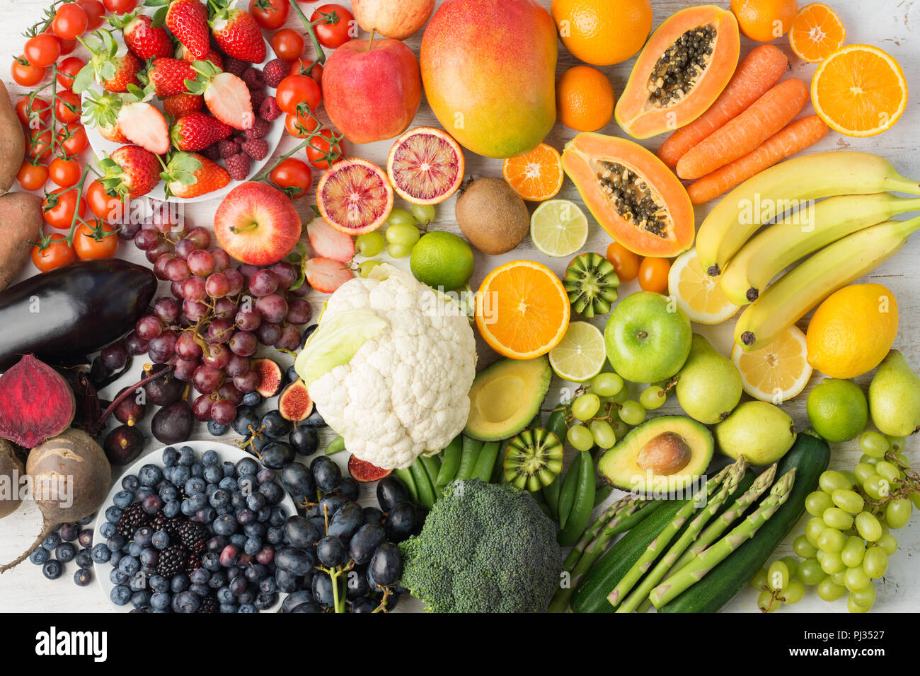 Healthy eating background, assortment of different fruits and vegetables in rainbow colours on the off white table arranged in a rectangle, top view, selective focus Stock Photo