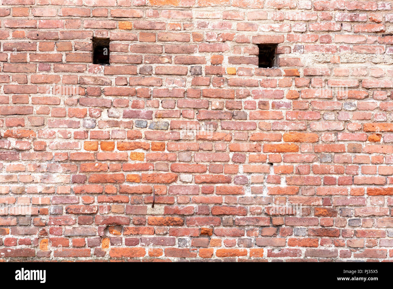 red adobe bricks wall background, with two vent holes Stock Photo - Alamy