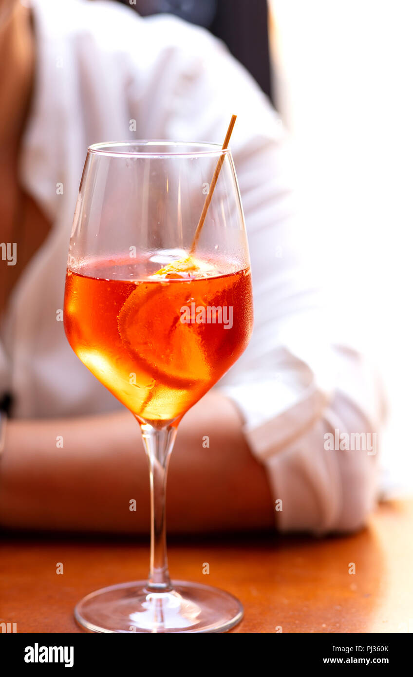 fresh aperol cocktail on a brown table with a blurred person as background Stock Photo