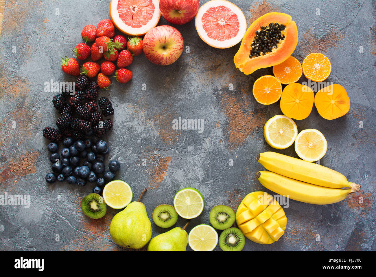 https://c8.alamy.com/comp/PJ3700/rainbow-color-fruits-arranged-in-a-circle-strawberries-blueberries-mango-orange-grapefruit-banana-apple-grapes-kiwis-papaya-on-the-grey-back-PJ3700.jpg