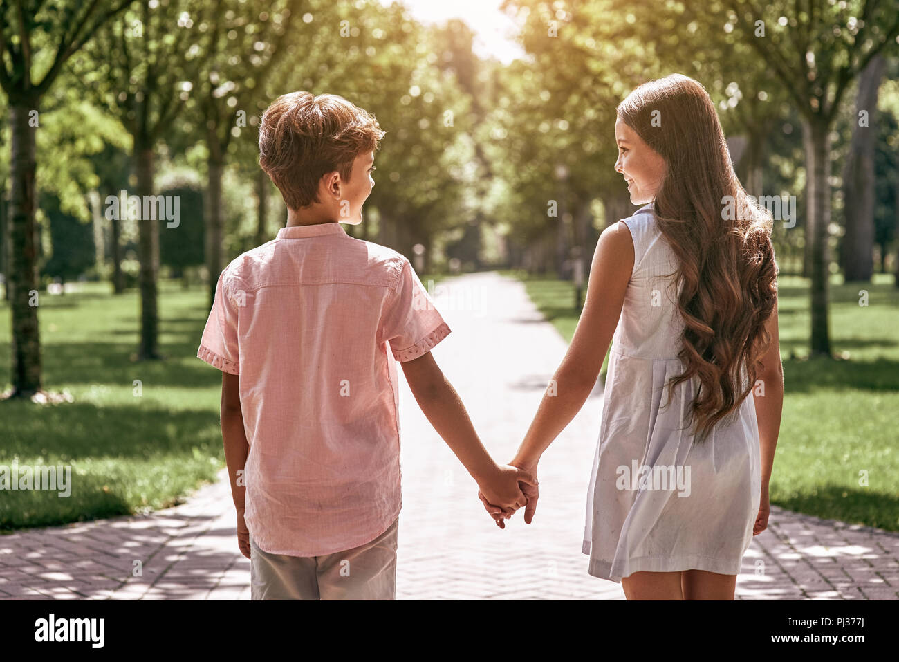 Friendship. Little boy and girl walking on the road in the park  Stock Photo
