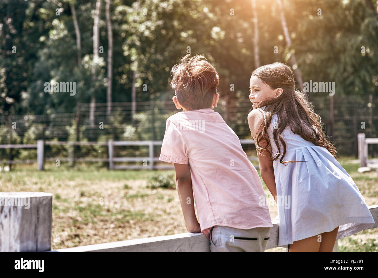 Friendship. Little boy and girl together outdoors leaning on fen Stock