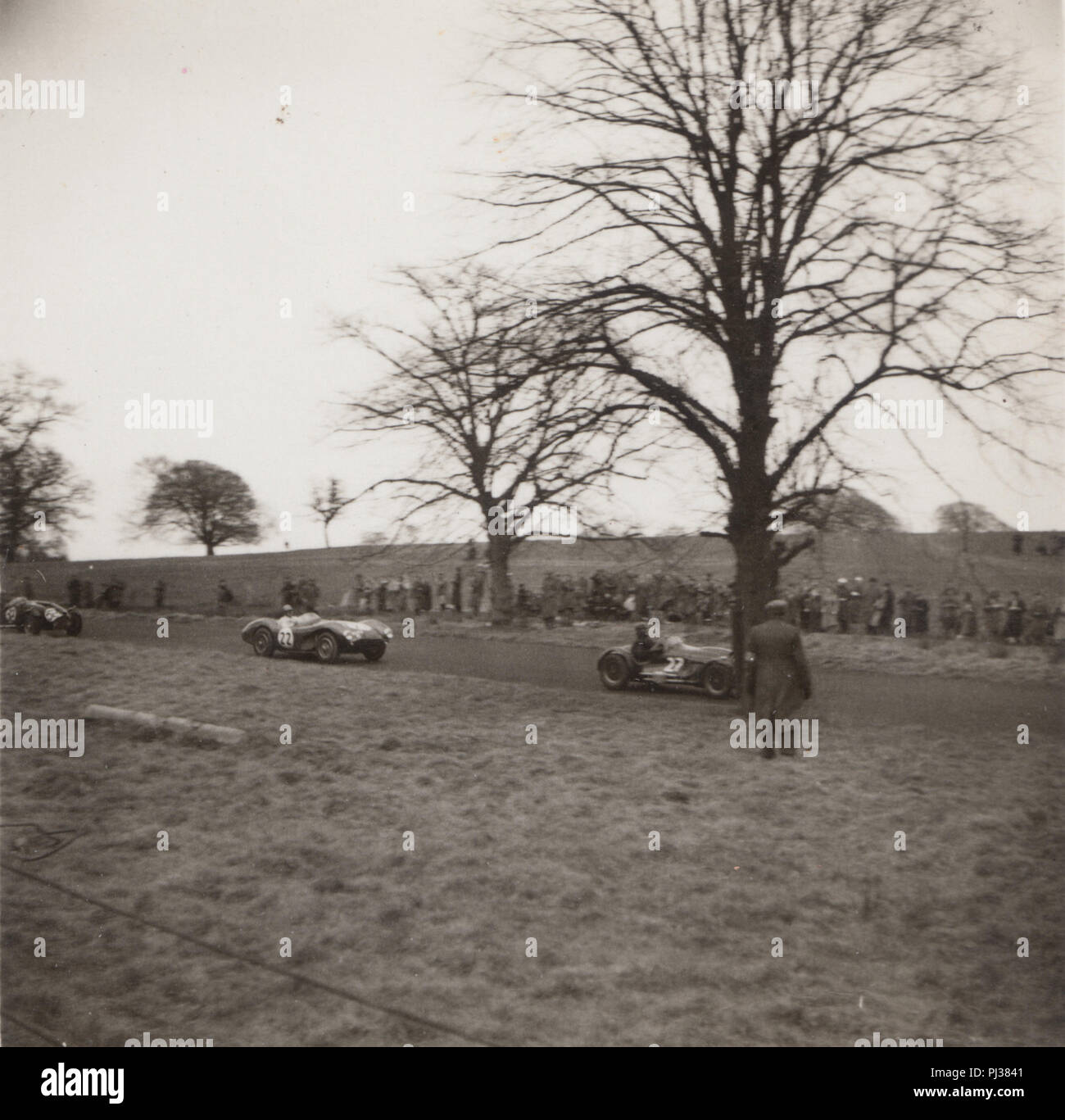 Vintage Photograph of British Motor Racing Cars With Spectators Lining The Roadside Stock Photo