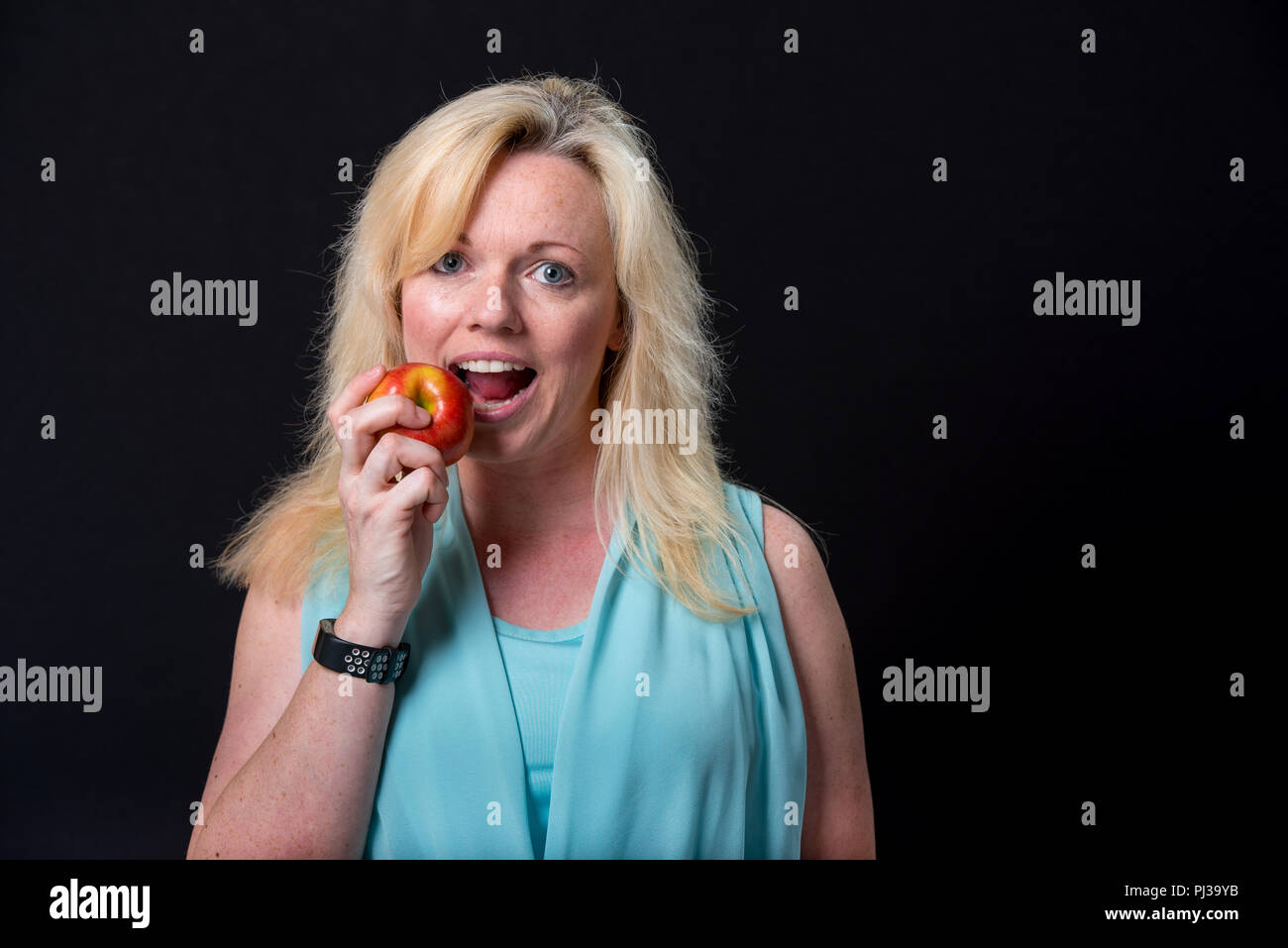 Blonde woman eating an apple Stock Photo