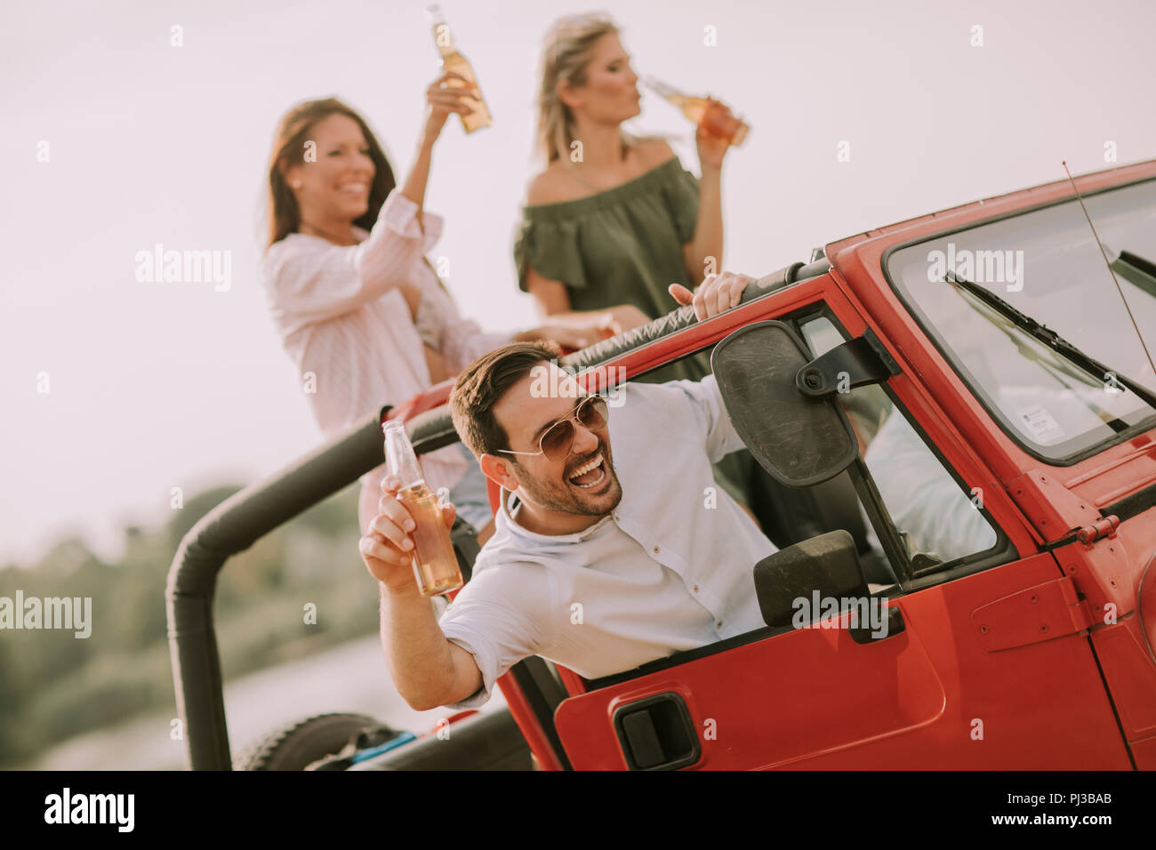 Young people having fun traveling together in convertible car and