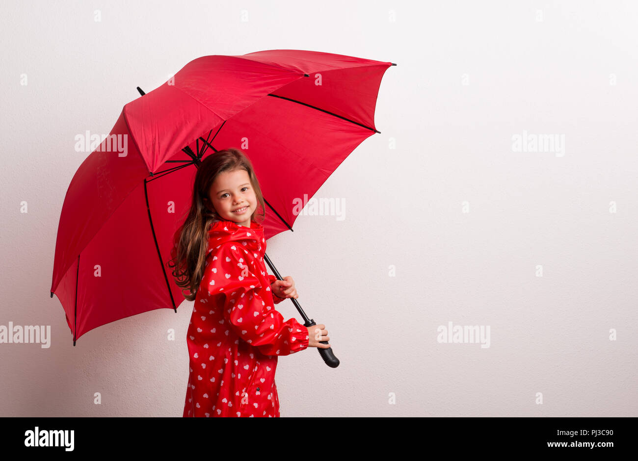 A small girl under an umbrella on a white background. Copy space. Stock Photo