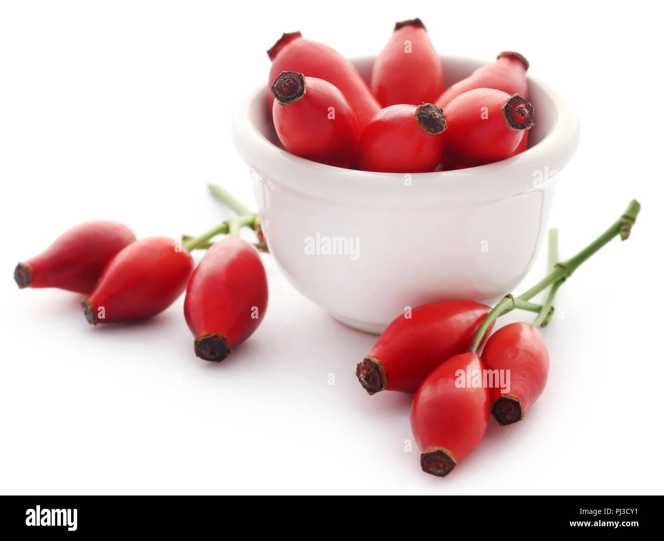 Medicinal rose hips in bowl over white background Stock Photo - Alamy