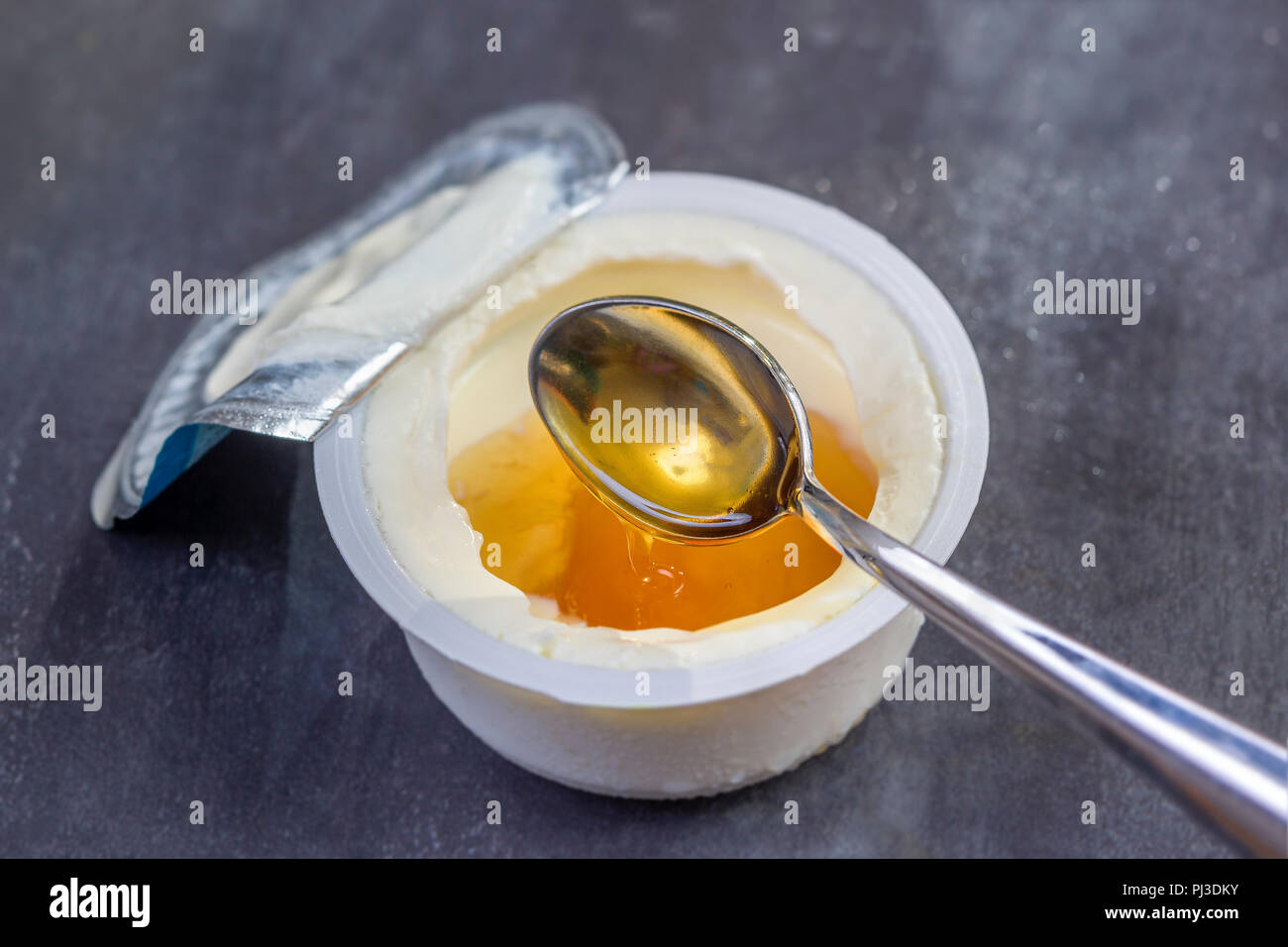 Honey Yogurt. Greek yogurt with honey in a plastic pot with honey and spoon Stock Photo