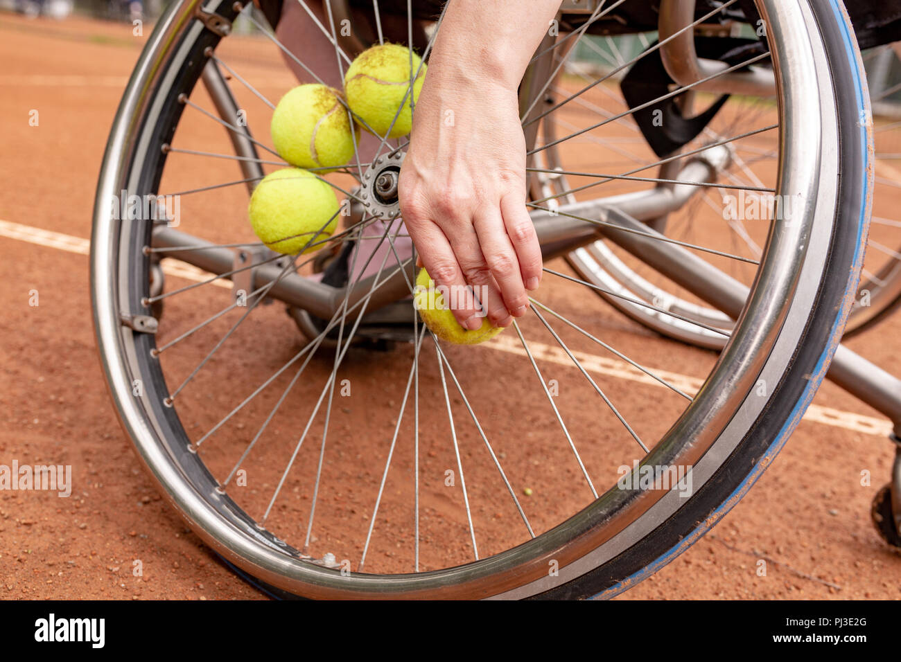 Disabled young woman on wheelchair playing tennis on tennis court