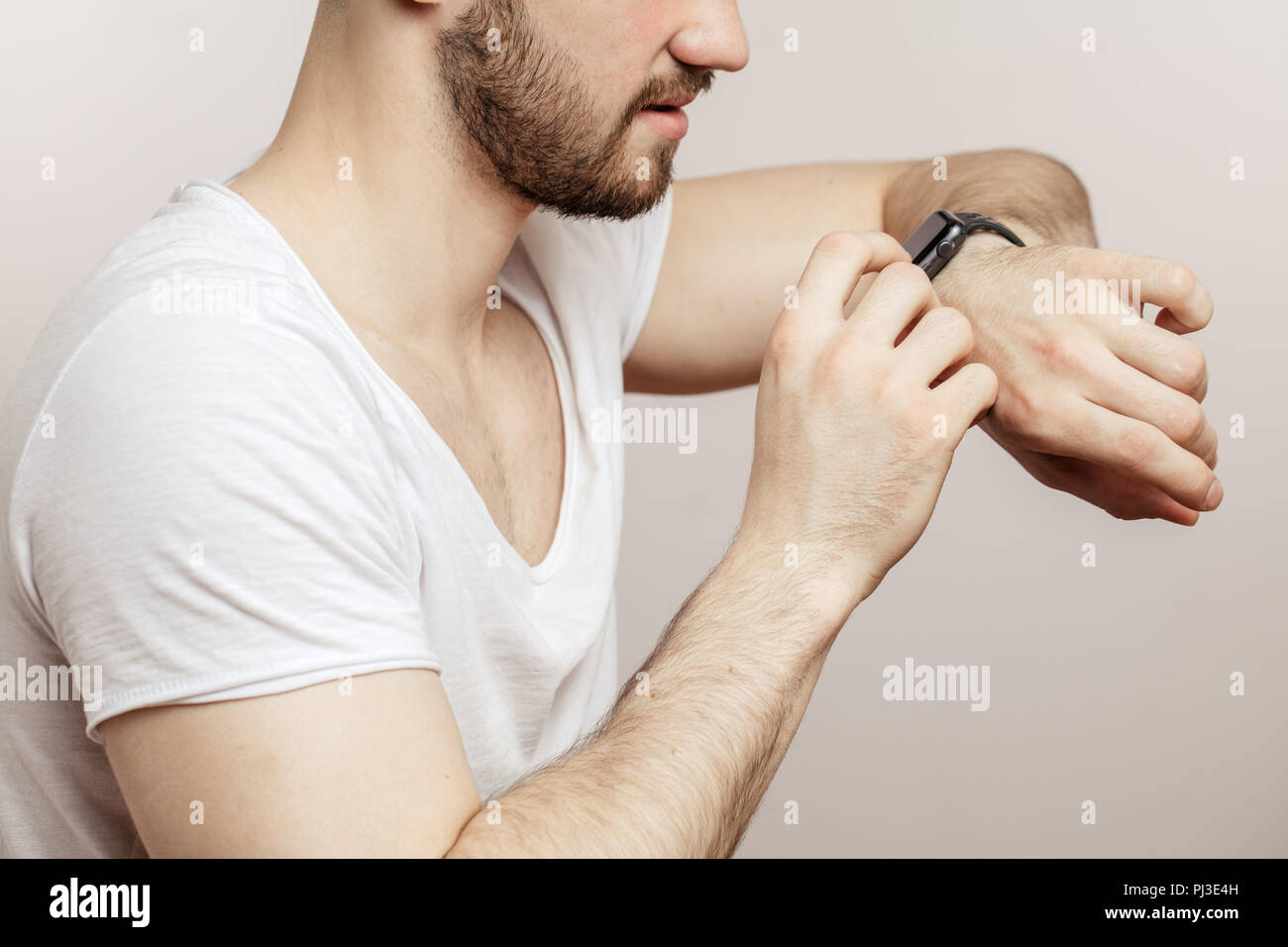 man using his smart watch while standing isolated on white background Stock Photo