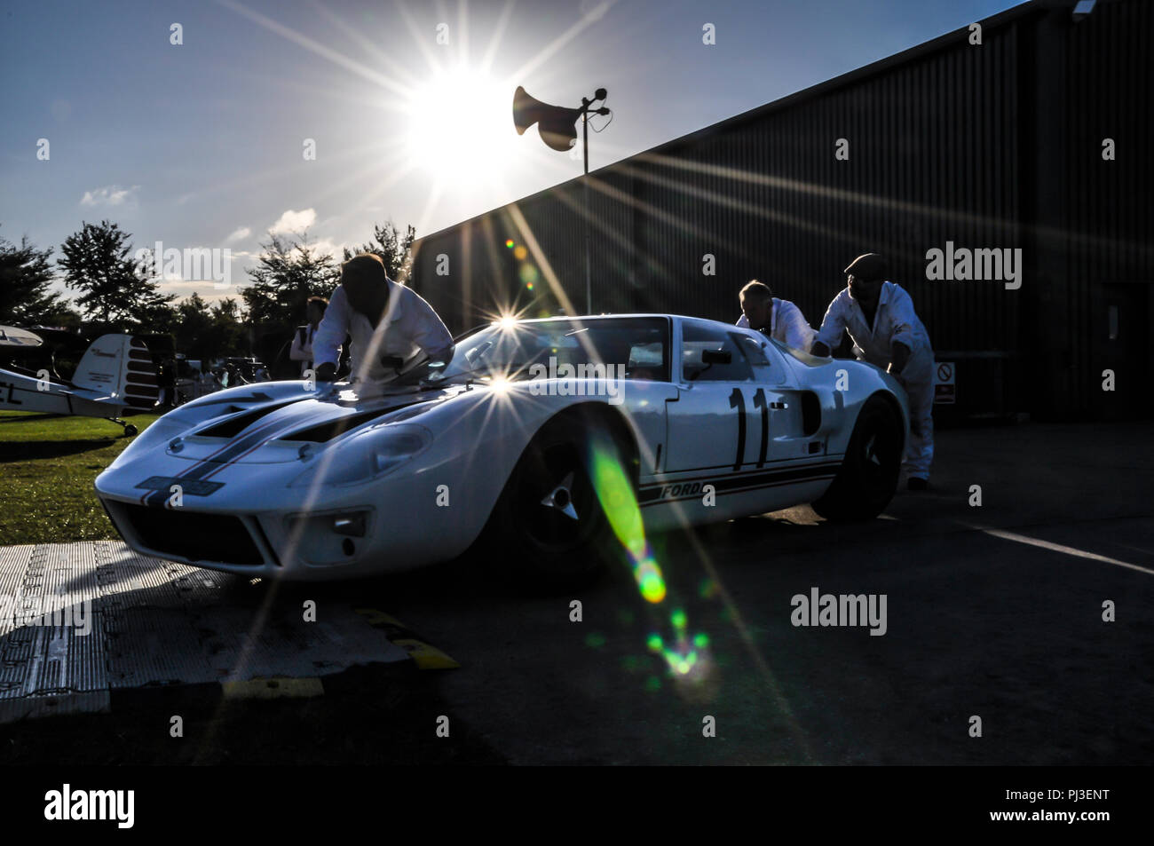 Mechanics pushing a Ford GT40 out in low sun at the Goodwood Revival. Le Mans era Sports prototype racing car Stock Photo
