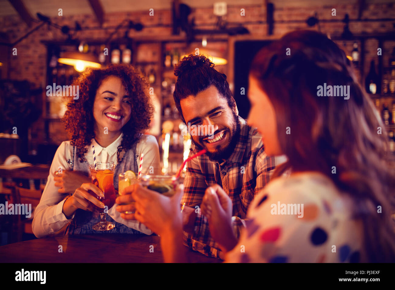 Young friends interacting with each other having drinks Stock Photo