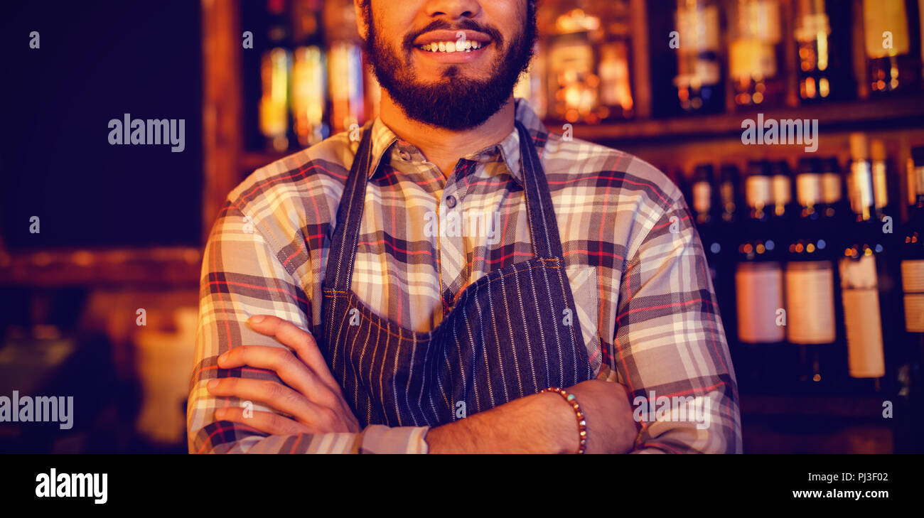 Portrait of smiling waiter standing with arms crossed Stock Photo